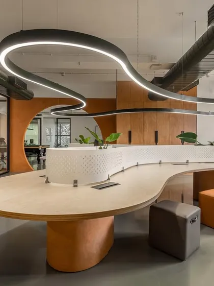 We designed the Hosachiguru office with an open-plan layout to foster collaboration. The centerpiece is this free-flowing, custom-designed workstation that eliminates hard edges and hierarchical barriers. A serpentine light fixture follows the curve of the desk, unifying the space and providing functional illumination.