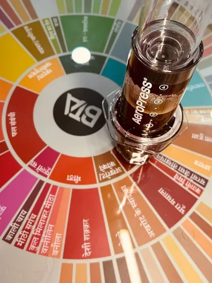 Another shot of our Hindi flavor wheel and an Aeropress, symbolizing the fusion of global coffee culture with local accessibility.