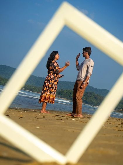 A candid, conversational moment from the same framed beach shoot. The prop helps to focus the viewer's attention on their interaction and expressions.