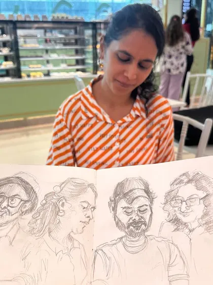 One of my models for the day sitting behind the sketchbook that features her portrait. It's always fun to show people the finished piece right after drawing them.