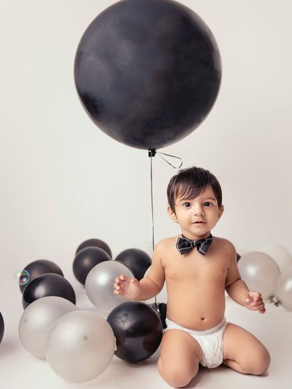 Classy and adorable in a bow tie and balloons. This simple, elegant setup is perfect for creating timeless portraits that celebrate your little one's personality.