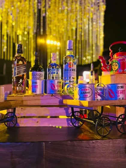 For a full Bollywood dhamaka, I bring the fun with quirky, custom props. This setup features hand-painted kettles and miniature carts displaying premium spirits, adding a playful and filmy touch to your cocktail party.