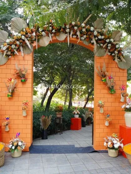 The main entrance arch for the orange-themed Haldi, decorated with an abundance of flowers and baskets of marigold petals.
