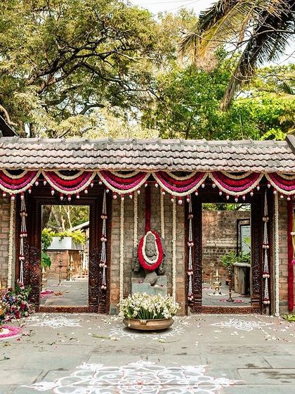 The entrance to a wedding venue, beautifully decorated in a traditional South Indian style with brick, wood, and marigold flowers.