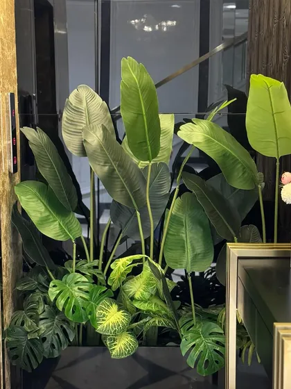 This tall arrangement of artificial Bird of Paradise and Monstera plants makes a grand statement in a luxurious entryway, perfectly complementing the marble walls and gold accents.
