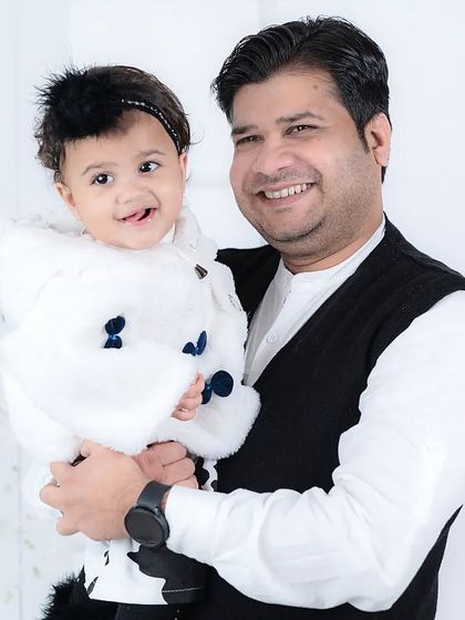 A father holds his smiling daughter, who is sticking her tongue out playfully. A perfect capture of a child's personality and a father's love.