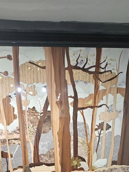 A beautiful wall mural created with wood and stone inlay, depicting a forest scene. This showcases our skill in combining different natural materials.