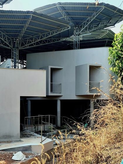 A view of the TAPMI Centre from the side during construction, showing the raw concrete forms and the underlying structure of the parasols.