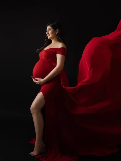 For moms who want a bold and dramatic statement, I use vibrant gowns from my studio wardrobe and techniques like fabric tossing to create powerful, dynamic maternity portraits against a classic black backdrop.