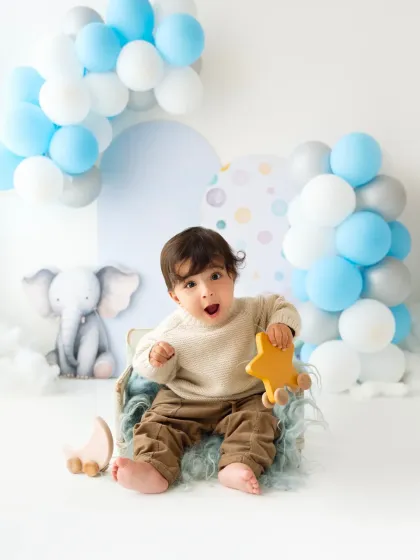 A baby boy makes a surprised and happy face during his first birthday celebration shoot. Capturing these expressions is what makes baby photography so fun.
