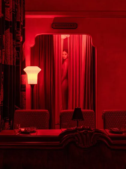 A provocative and artistic shot, where a figure is glimpsed behind a red curtain, adding to the theatrical and mysterious quality of the space.