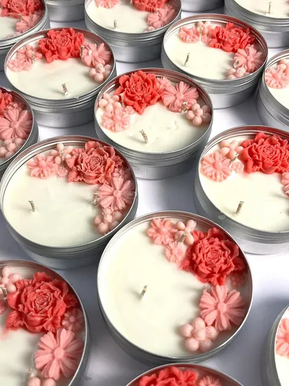 Our floral tin candles are a simple yet beautiful gift. This image showcases the delicate arrangement of pink and red wax flowers, handcrafted to create a charming decorative piece.