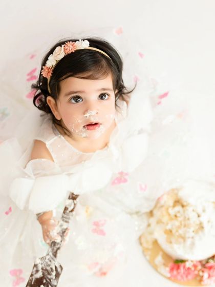An aerial view of a butterfly-themed cake smash, showing the beautiful mess and a cute, frosting-smudged face.