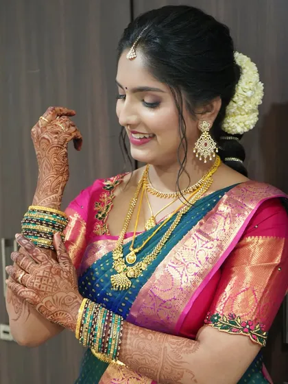 A happy, candid moment from a Varapooje event. The bride's makeup is radiant and enhances her smile, and the traditional braided hairstyle is adorned with fresh jasmine.