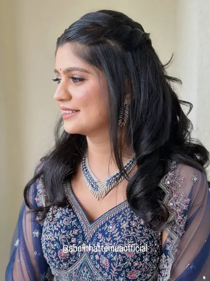 A side profile showing the flawless base and soft hairstyle for this sangeet look. The makeup is designed to be long-lasting to withstand a night of dancing.