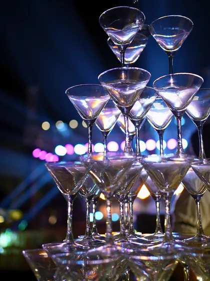 A classic champagne tower adds a touch of indulgence and celebration to the party. It's a perfect visual element for a glamorous theme like the Roaring '20s, inviting guests to toast the night away.