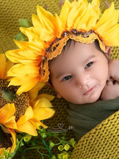 A beautiful, awake shot of our little sunflower. Her bright eyes and sweet expression, framed by the yellow petals, make this a truly captivating portrait.