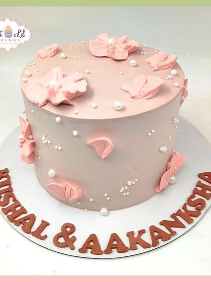 A delicate and romantic anniversary cake for Kushal and Aakanksha, decorated with pink petals and pearls.