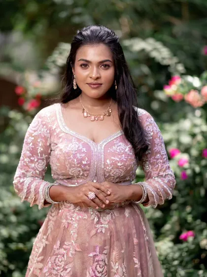 A model posing in a pink lehenga, with a focus on her beautiful, flowing hair and subtle makeup.