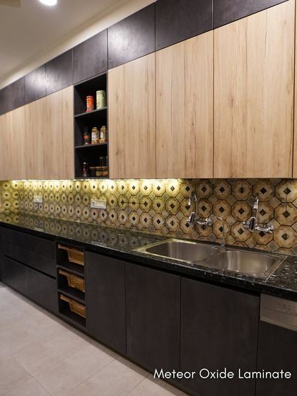 The dual-tone cabinetry in this kitchen pairs a natural wood finish on top with a dark, textured laminate below. Under-cabinet lighting highlights the unique backsplash.