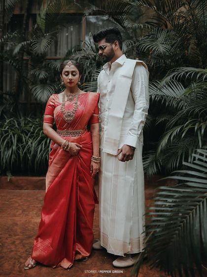 A classic, poised portrait of the bride and groom, their traditional attire looking stunning against a backdrop of lush greenery.