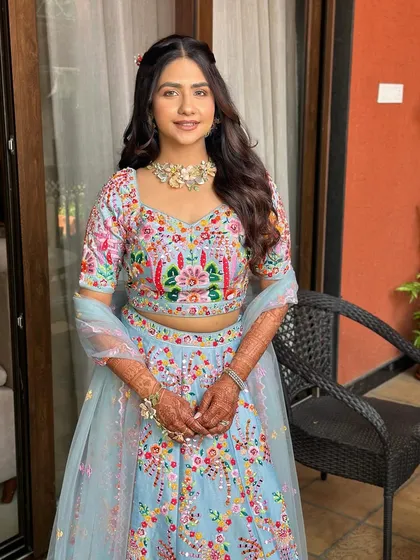 A soft look for a girl in her soft girl era. This bride is wrapped in sunshine and blessings, with a minimal glam look that matches her pastel blue floral lehenga.
