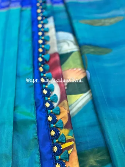 A close-up of a hand-painted fabric, showing the artistic details that can be incorporated into our custom designs, complemented by a crocheted tassel border.