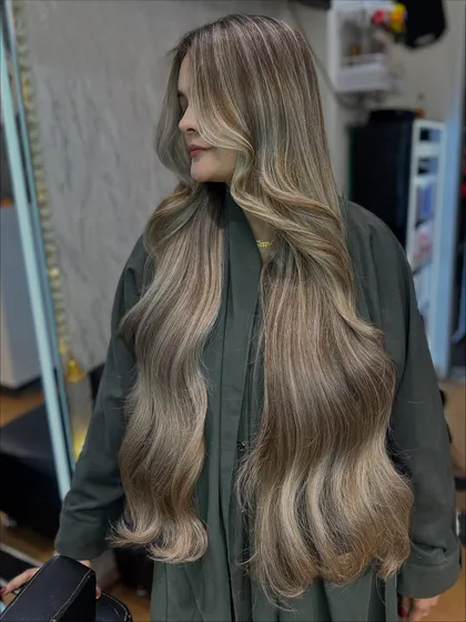 The way this icy ash blonde hair moves is just magical. The long layers and soft waves show off the intricate tones and expert coloring technique.