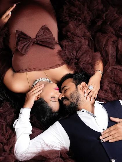 An intimate top-down shot of a couple in a nest of brown tulle. The rich, earthy tones and their close embrace create a warm, secure, and deeply romantic portrait.