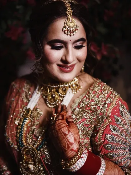 A radiant bride, her smile as beautiful as her mehandi. The henna on her hand adds to her overall bridal glow.