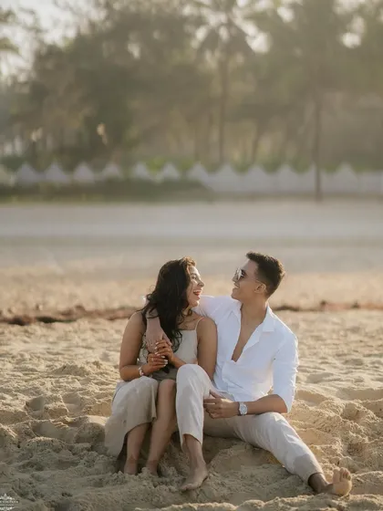 A relaxed portrait of a couple sitting on the sand and sharing a laugh. These casual, comfortable moments are a key part of a candid pre-wedding shoot.