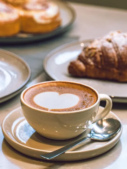A moment of pure delight. My rich cappuccino, with its perfect heart-shaped latte art, pairs beautifully with a freshly baked almond croissant.