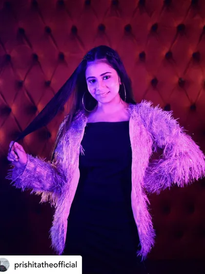 Another shot of Prishita in the fuzzy jacket, this time under dramatic purple lighting. This shows how an outfit can transform under different lighting conditions on a set.