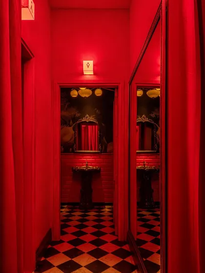 The restroom entrance, where a mirror reflects the checkerboard floor and jungle-themed wallpaper, creating a moment of unexpected delight.
