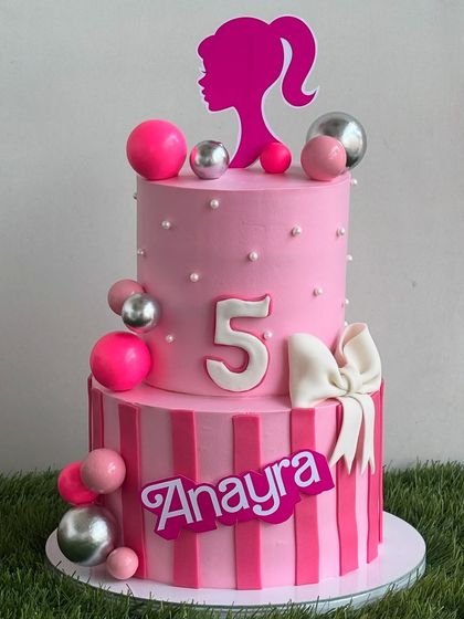 This two-tier Barbie cake is a dream come true for any fan. It features pink stripes, a Barbie silhouette, and shiny spheres for a touch of glam, all crafted with our light whipped cream frosting.