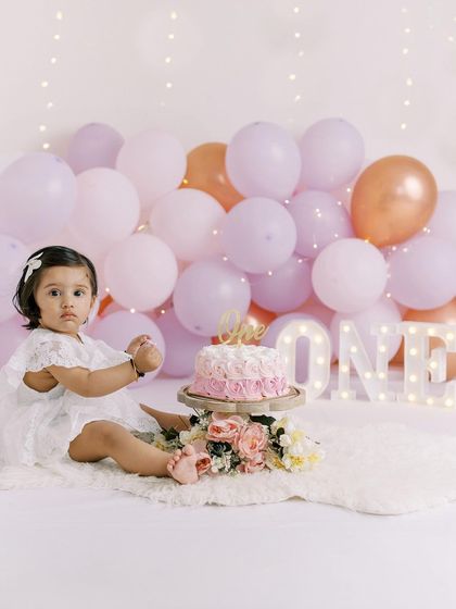 A full view of the beautiful cake smash setup, with balloons, flowers, and the "ONE" sign, all arranged in the family's home.