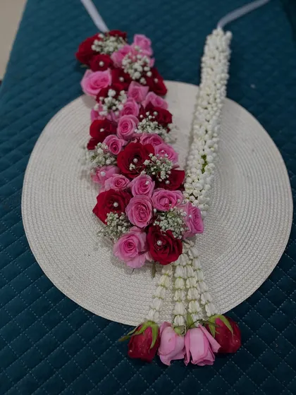Here is a detailed look at a kanthi made with pink and red roses, interspersed with jasmine. This style is versatile and can be used for deities or as a smaller wedding garland.