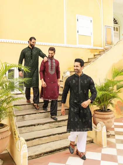 Step out in effortless tradition. This image captures the joy and camaraderie of a celebration, with friends dressed in our comfortable and stylish kurta sets in shades of black, maroon, and dark green, each featuring unique embroidery details.