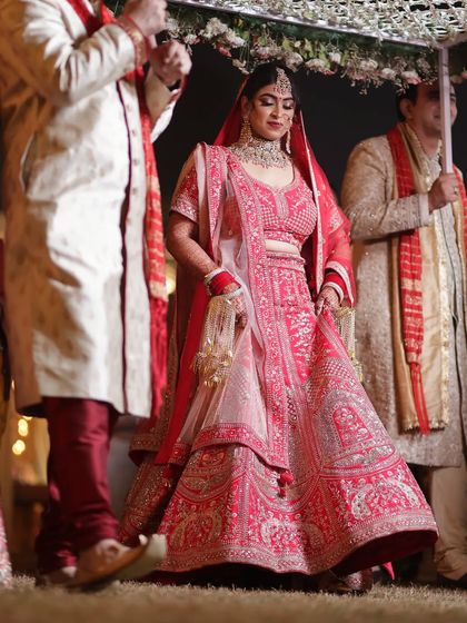 The full bridal entry. Her stunning red lehenga and perfectly matched makeup create an unforgettable vision.