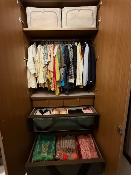 This closet combines hanging space with deep, glass-fronted drawers for folded garments. We organized the client's heavy Indian wear in the drawers, using vertical folding to protect the embroidery and make each piece visible.