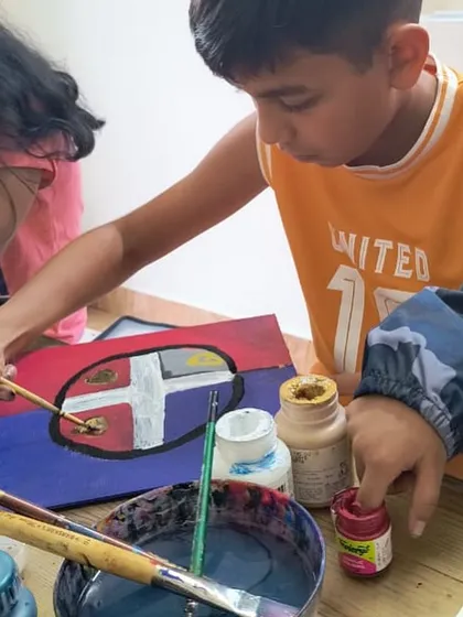 Teamwork makes the dream work. A young artist gets some help from his friend while painting, showing the collaborative spirit we foster in our studio.