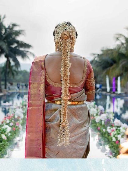 A shot of the bride's walk down the aisle, showcasing her beautiful South Indian bridal hairstyle and the floral decor lining the path.