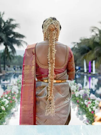 A shot of the bride's walk down the aisle, showcasing her beautiful South Indian bridal hairstyle and the floral decor lining the path.