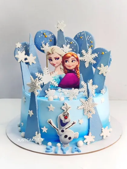 A cool-toned Frozen theme cake with edible snowflakes and chocolate spheres. This design focuses on a blue ombre effect and printed character toppers.