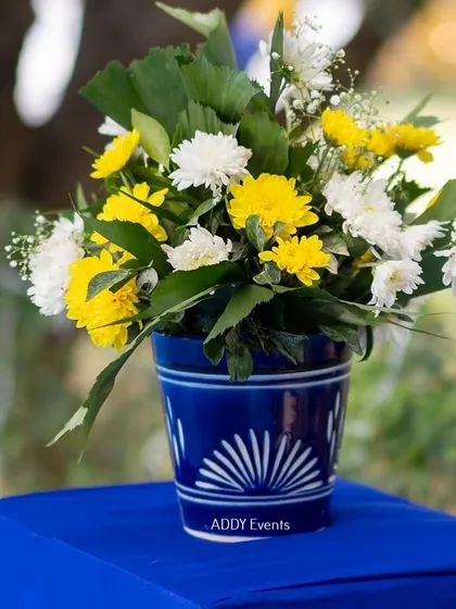 A close-up of a floral arrangement in a beautiful blue and white ceramic pot, part of the Santorini-themed decor.