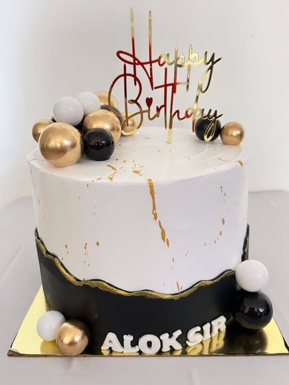 Another elegant cake design in black, white, and gold. The combination of a sharp bottom edge and gold splatter gives it a modern and sophisticated feel.