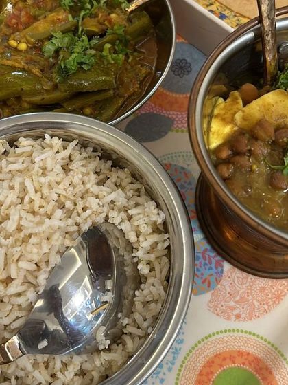 A simple yet delicious and healthy lunch plate with brown rice, kala chana curry, and a green vegetable sabzi.