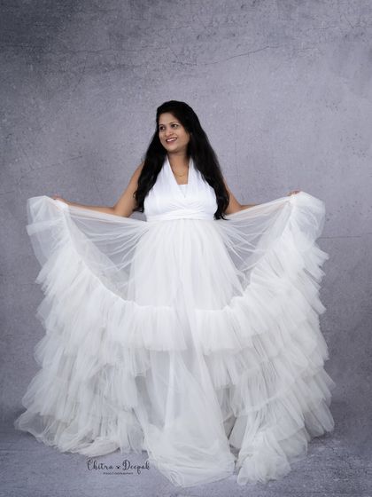 A joyful swirl in a white tiered gown. This shot is full of life and happiness, perfectly capturing the excitement of being a mom-to-be.
