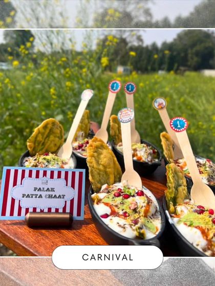 My popular Palak Patta Chaat served with carnival-themed labels. This dish is a crowd-pleaser, combining crispy spinach fritters with yogurt and chutneys for a perfect bite.