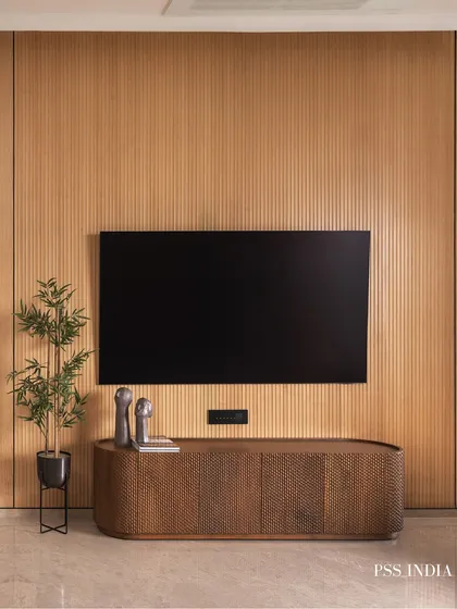 The TV wall is designed as a feature, not an afterthought. The screen is mounted on a fully paneled fluted wood wall, with a minimalist console below, creating a look that is both clean and warm.